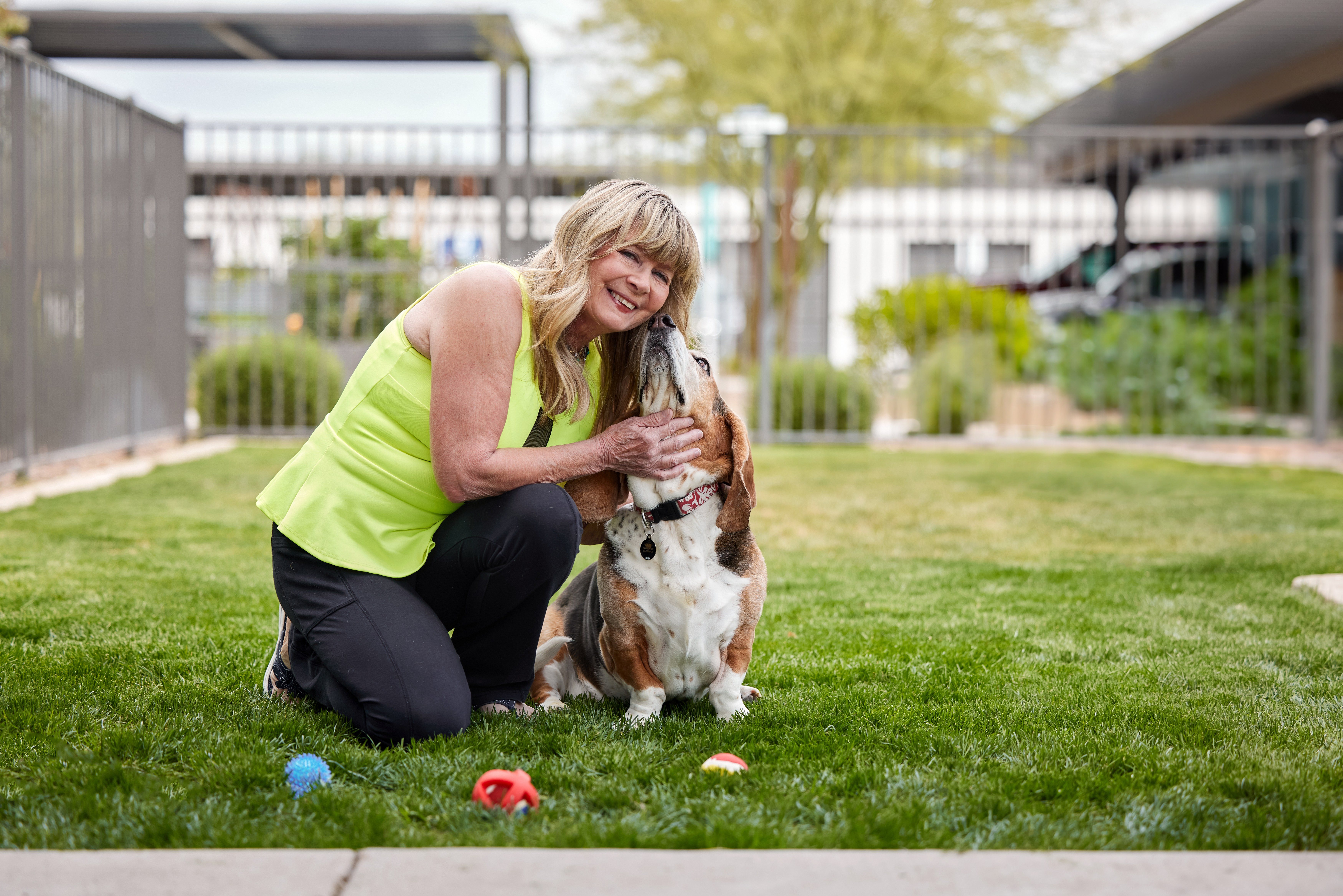 A woman in a green top is playing with a dog in a grassy area.